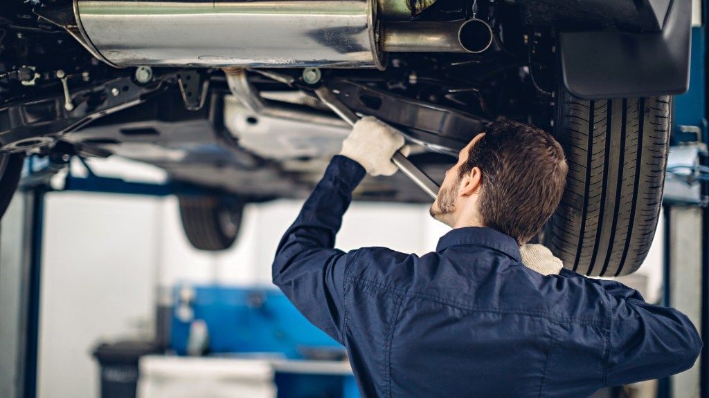 A man is working under a car with a wrench. | Karta Motorwerks