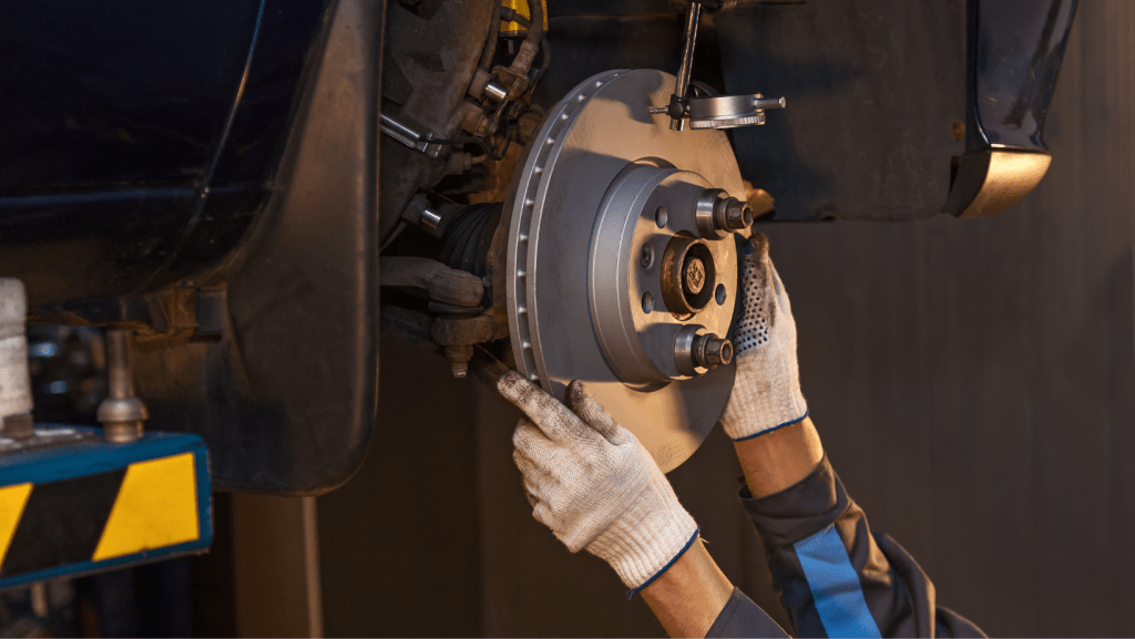 A man is fixing a brake on a car in a garage | Karta Motorwerks