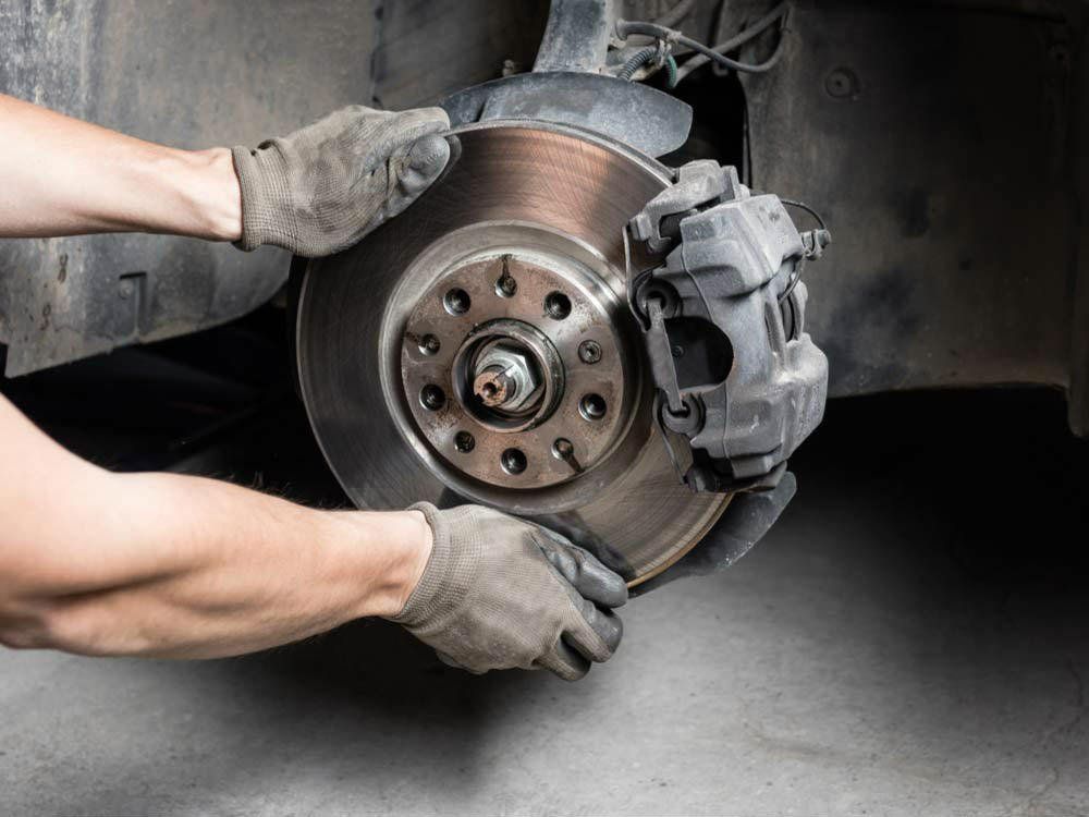 A man is fixing a brake disc on a car. | Karta Motorwerks