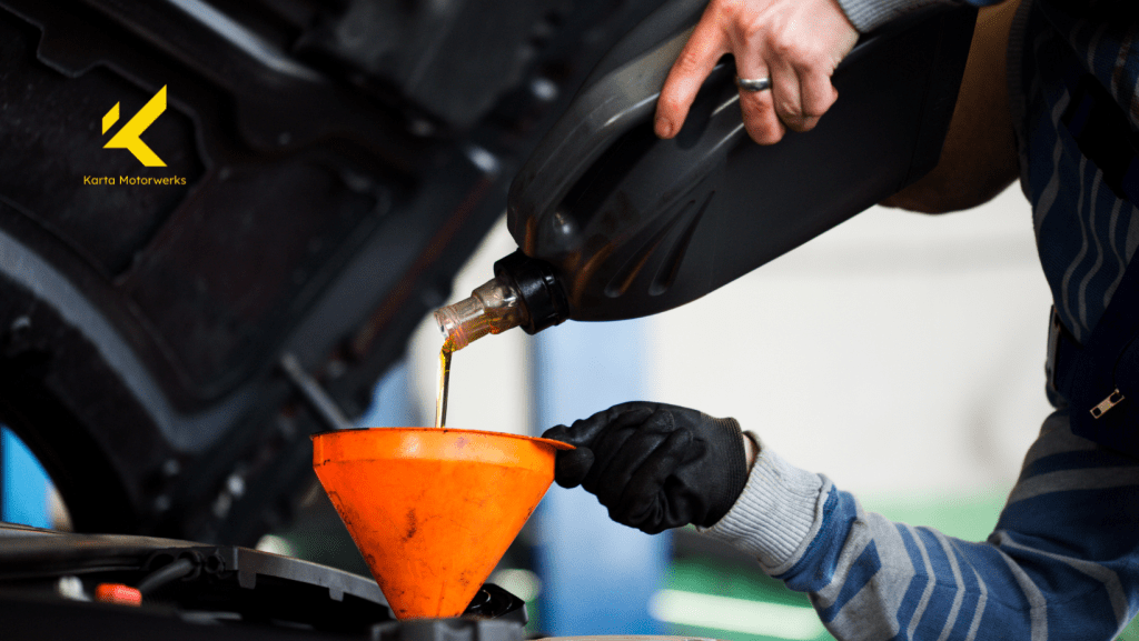 A man is pouring oil into a car through an orange funnel. | Karta Motorwerks