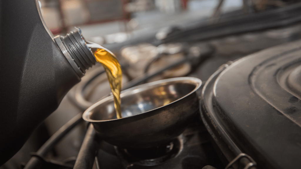 A close up of a person pouring oil into a car engine | Karta Motorwerks