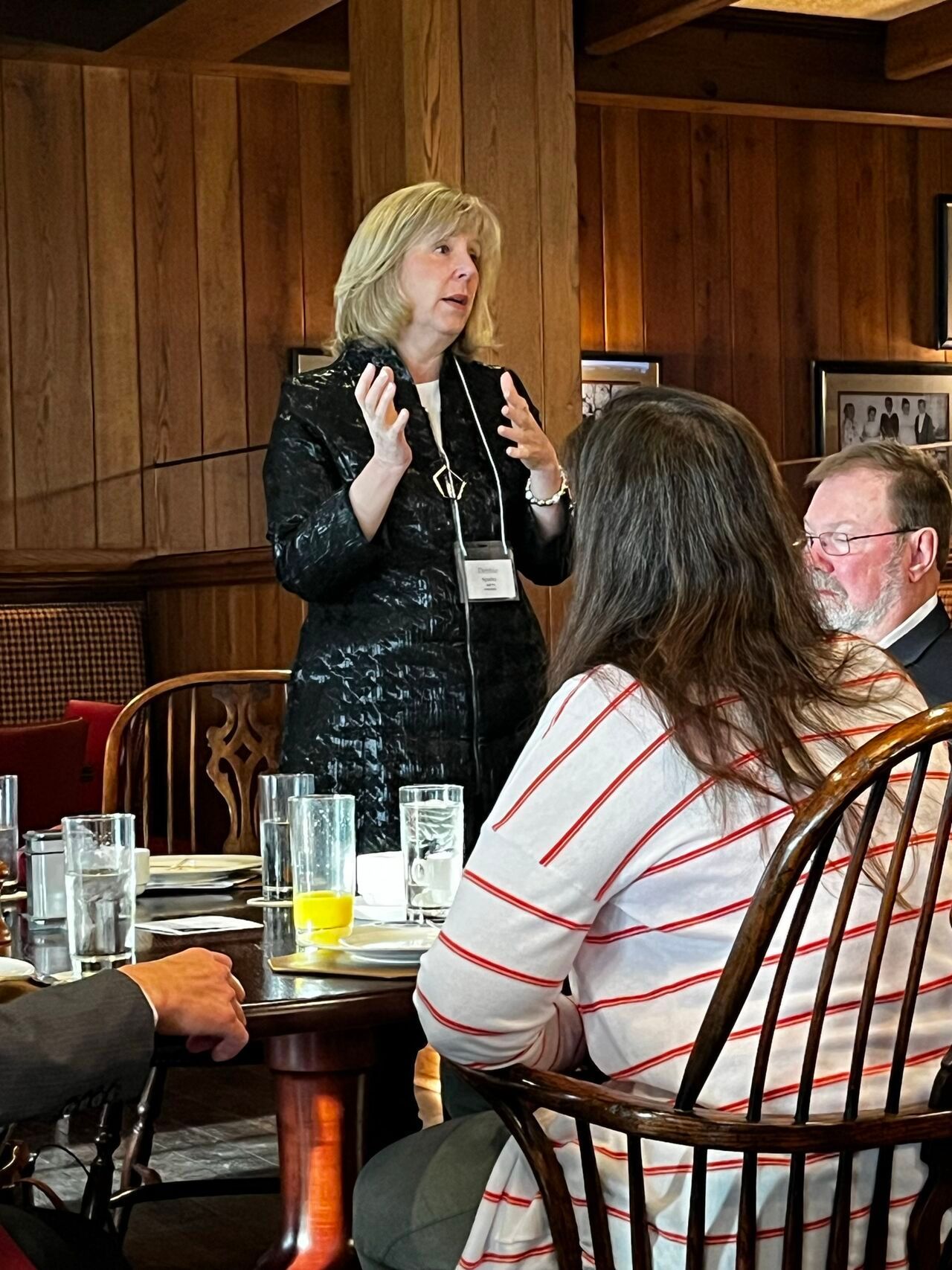 A woman is talking to a group of people sitting at a table.