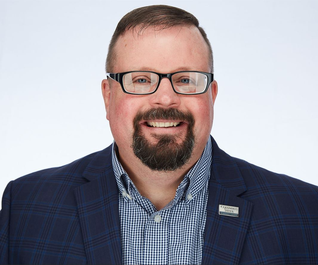 A man with a beard and glasses is wearing a suit.