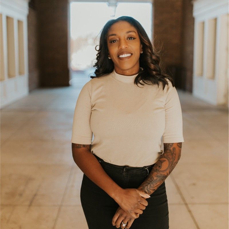 A woman with a tattoo on her arm is smiling for the camera