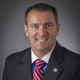 A man in a suit and tie is smiling for the camera