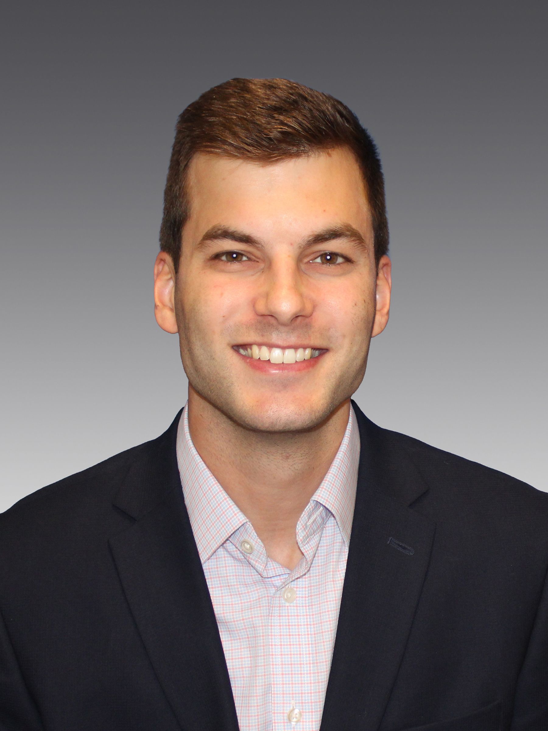 A man in a suit and white shirt is smiling for the camera.