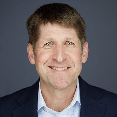 A man in a suit and plaid shirt is smiling for the camera.