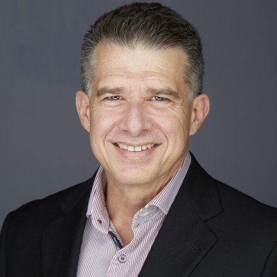 A man in a suit and striped shirt is smiling for the camera.