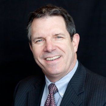 A man in a suit and tie is smiling for the camera.
