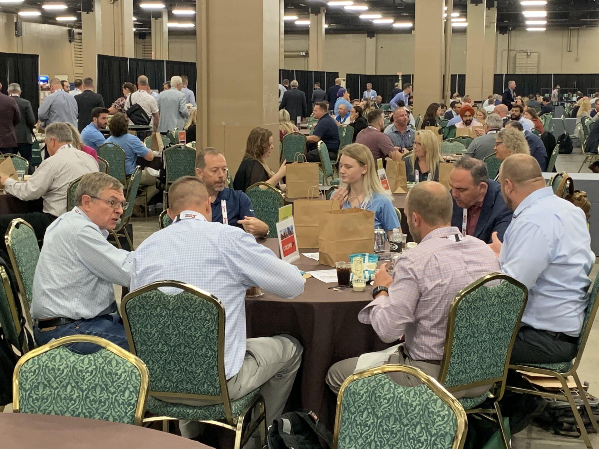 A group of people are sitting at tables in a large room.