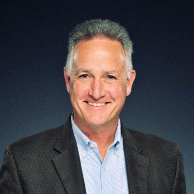 A man in a suit and blue shirt is smiling for the camera.