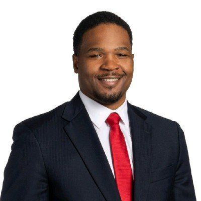 A man in a suit and red tie is smiling for the camera.