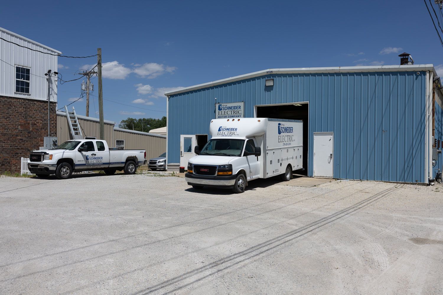 Two white trucks are parked in front of a blue building