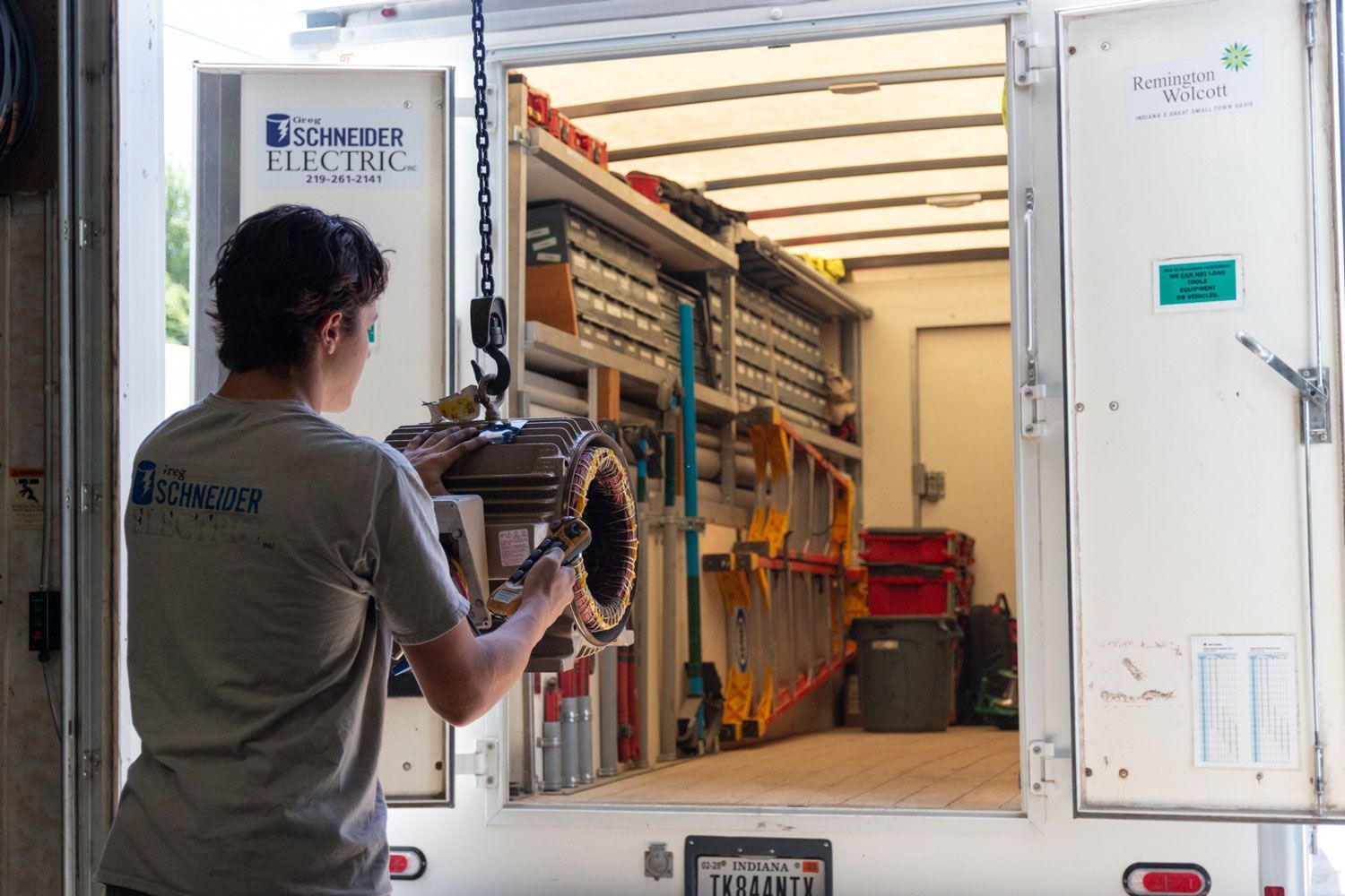 A man in a gray shirt is standing in front of a truck that says gsc woods