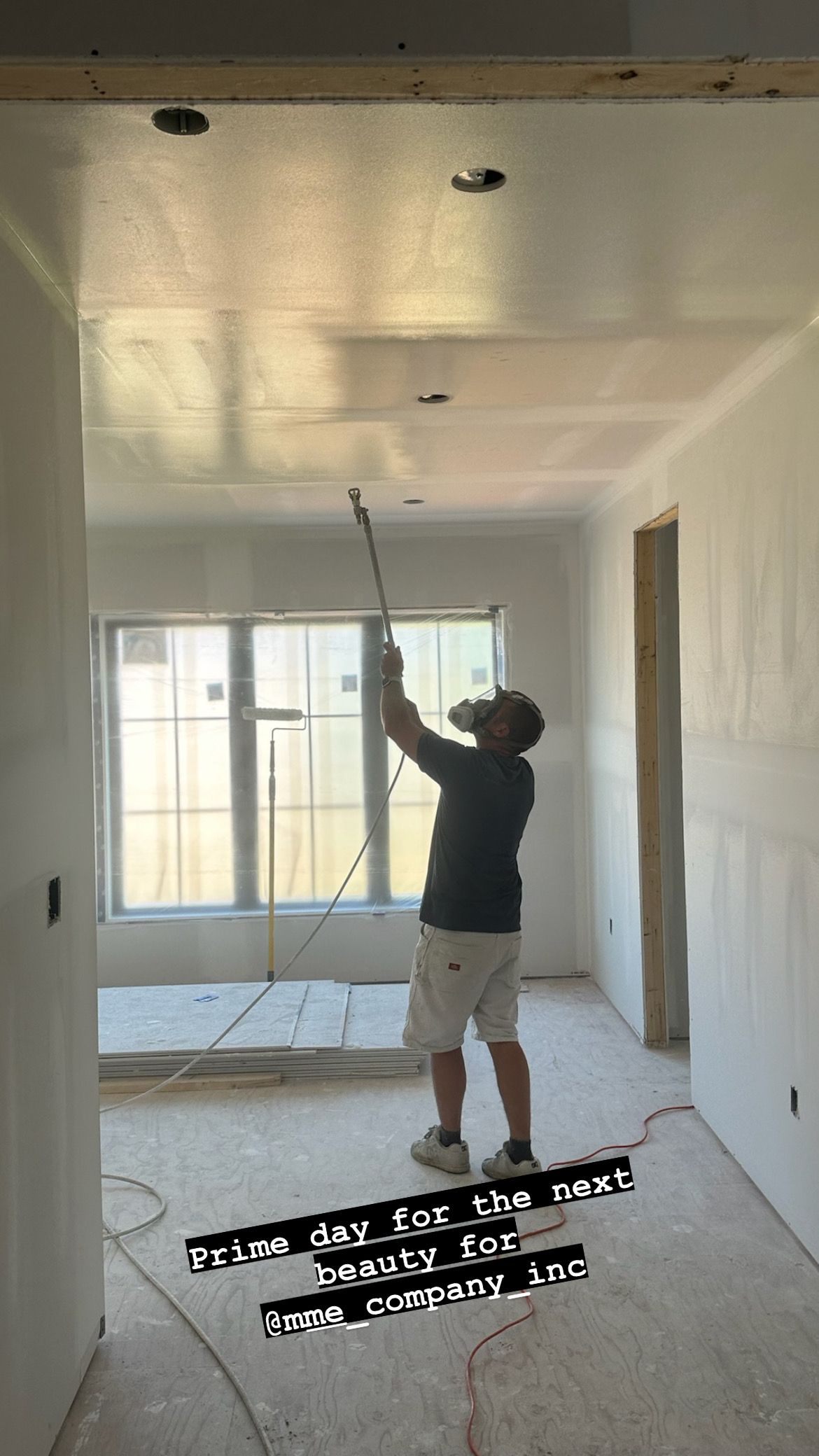 A man is painting the ceiling of a room.