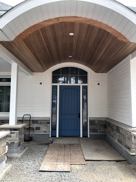 The front of a house with a blue door and a wooden ceiling