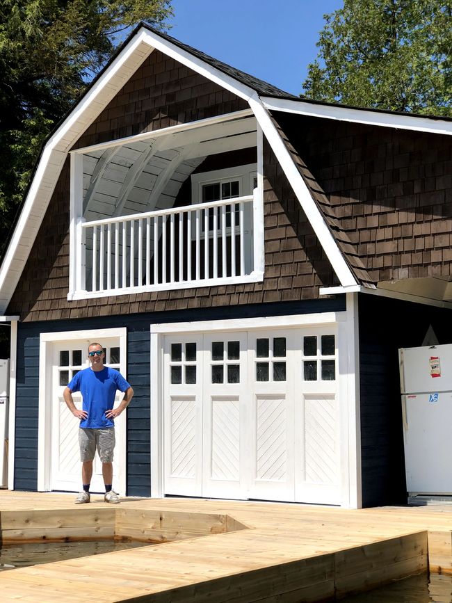 A man is standing in front of a garage with a balcony