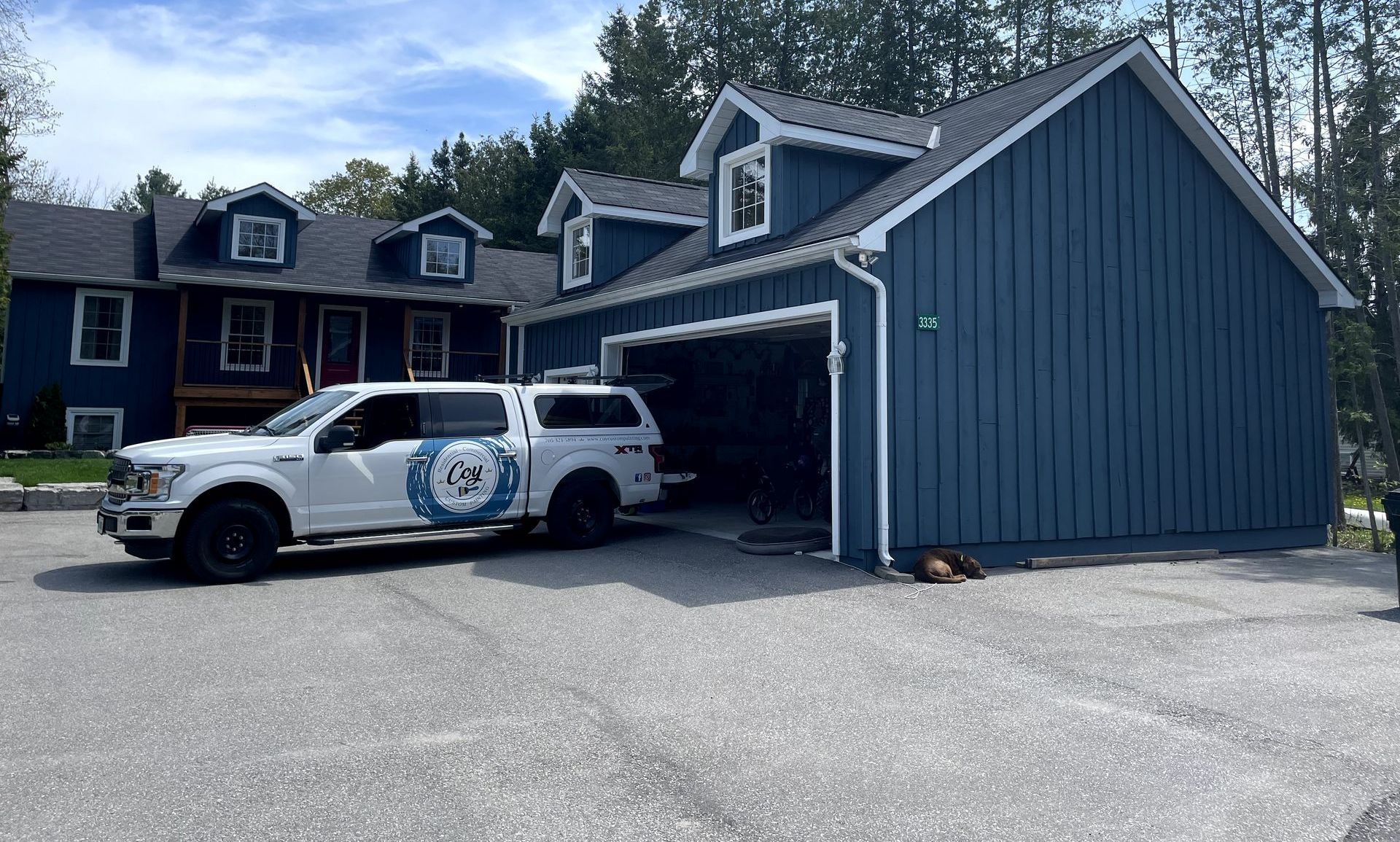 A white truck is parked in front of a blue house.