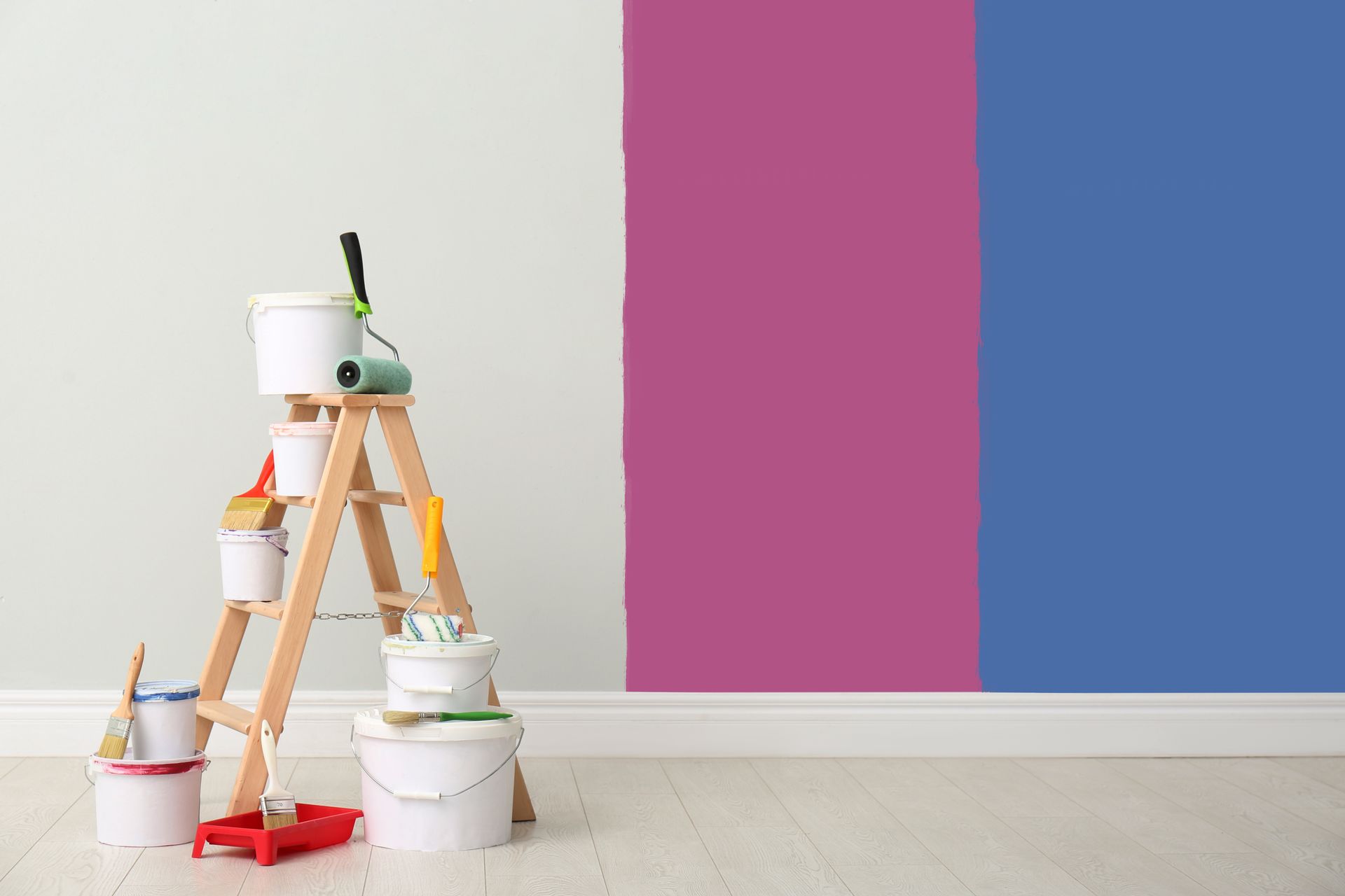 A wooden ladder with buckets of paint and paint rollers in front of a wall.
