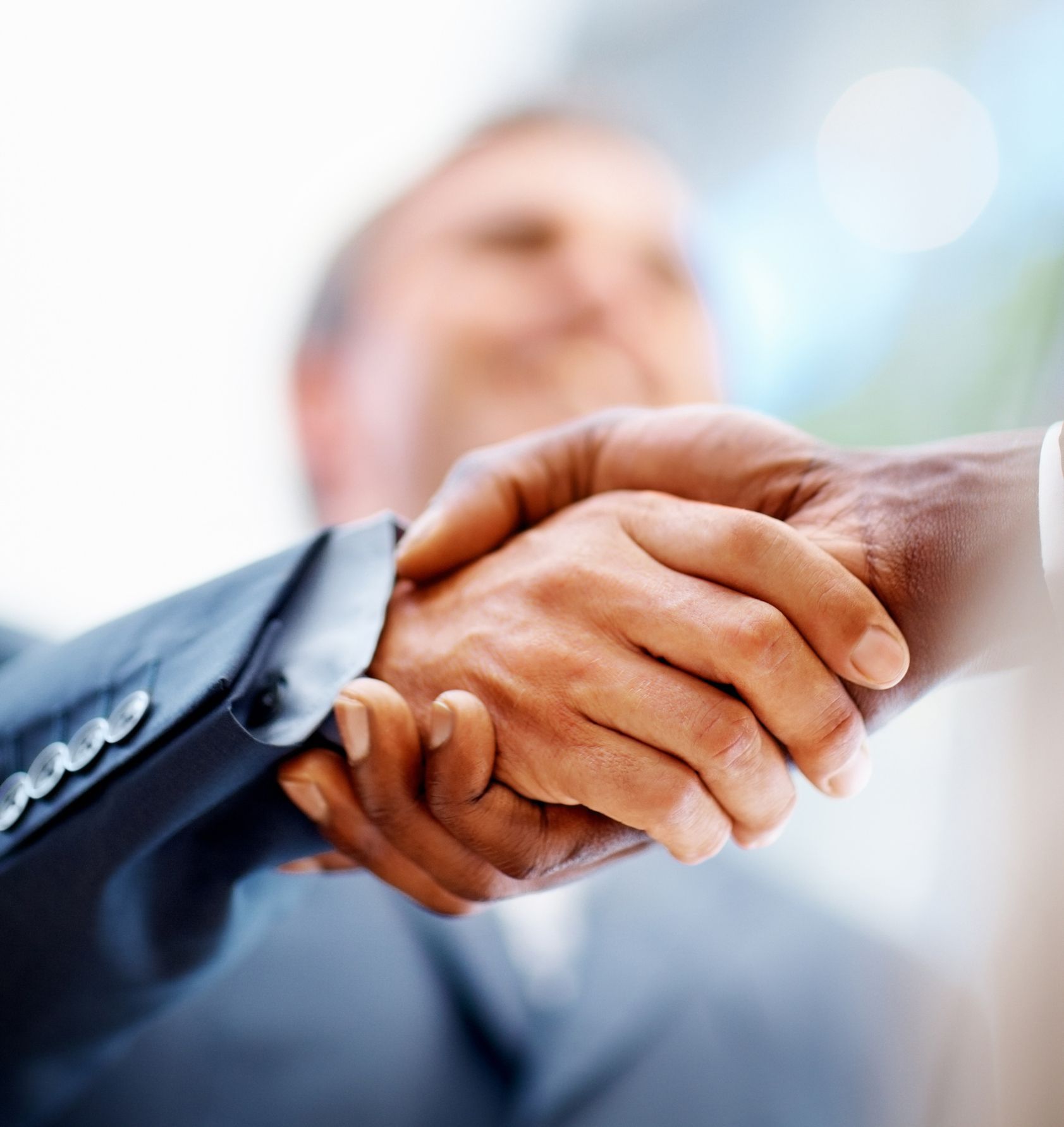 Two men in suits shaking hands in a business setting.