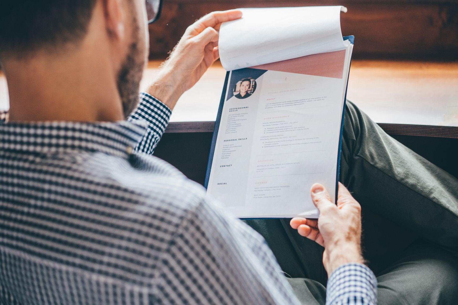 Person reviewing a resume held in a blue clipboard.