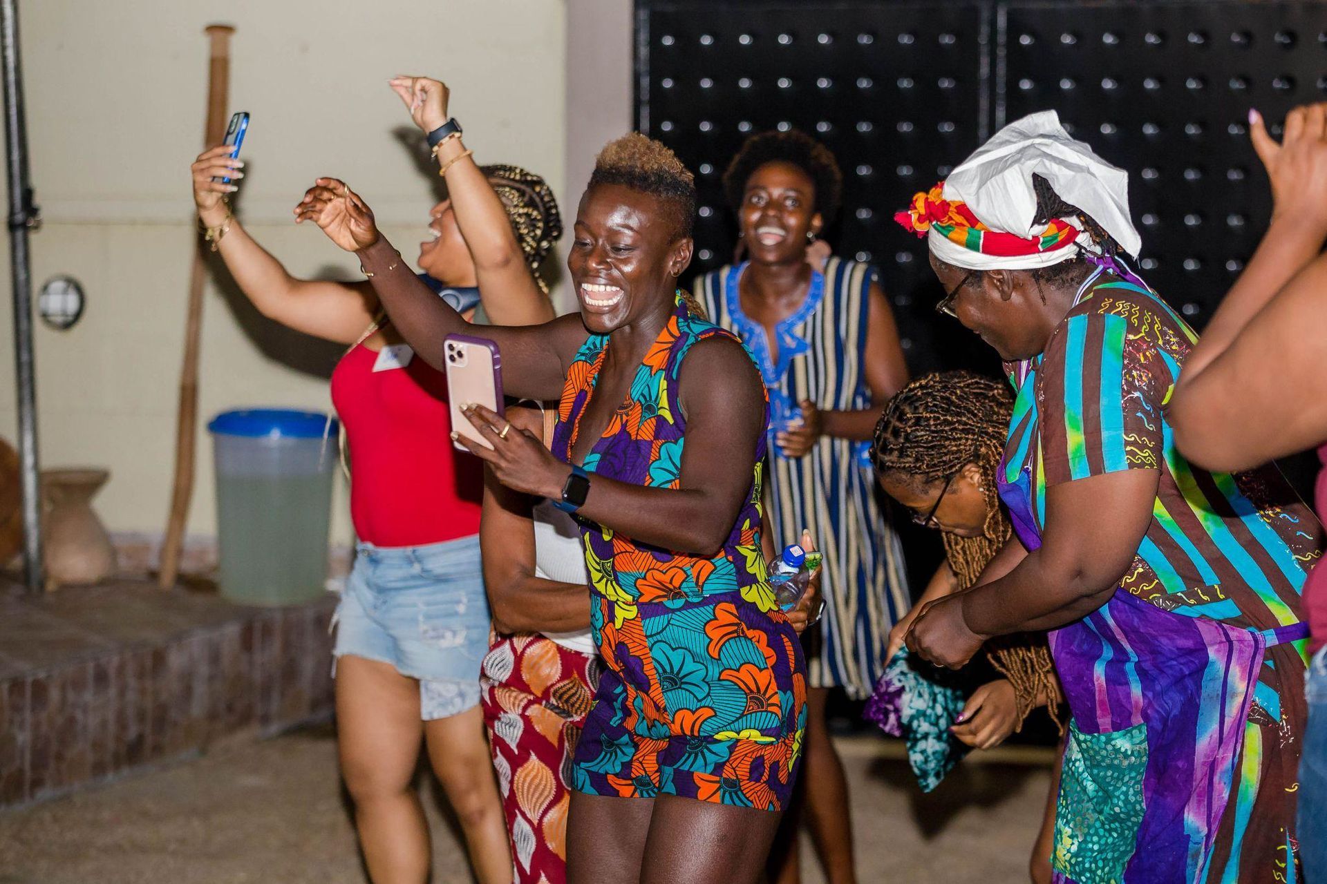 A group of women are dancing and taking selfies with their phones.