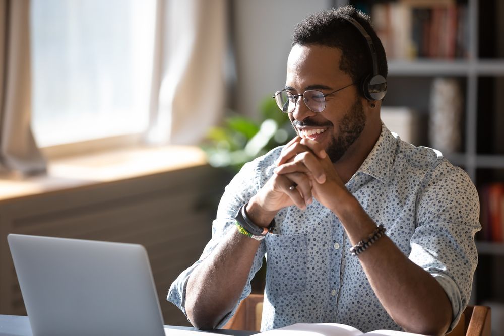 A man wearing headphones is sitting in front of a laptop computer.