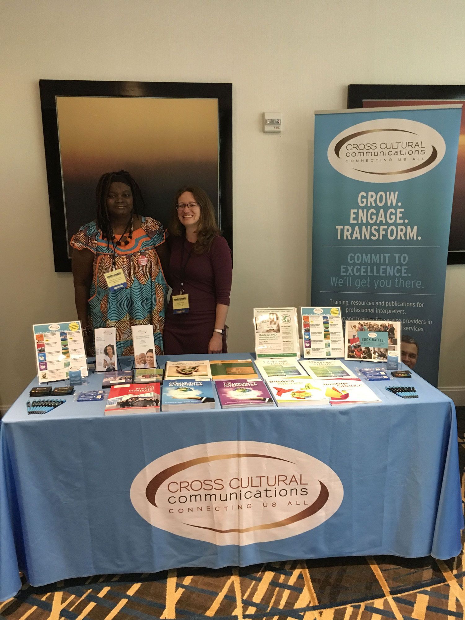 Two women are standing in front of a table at a conference.