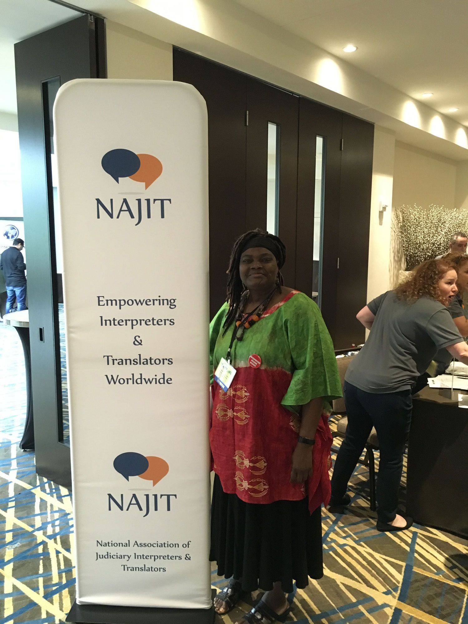 A woman is standing in front of a sign that says najit.