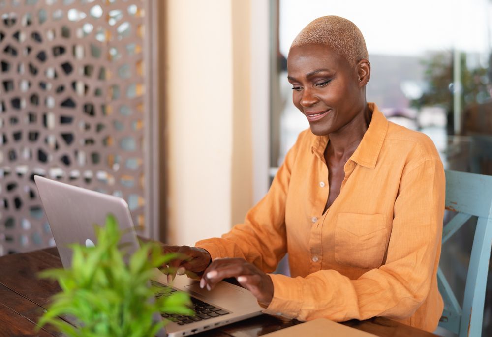 A woman is sitting at a table using a laptop computer.