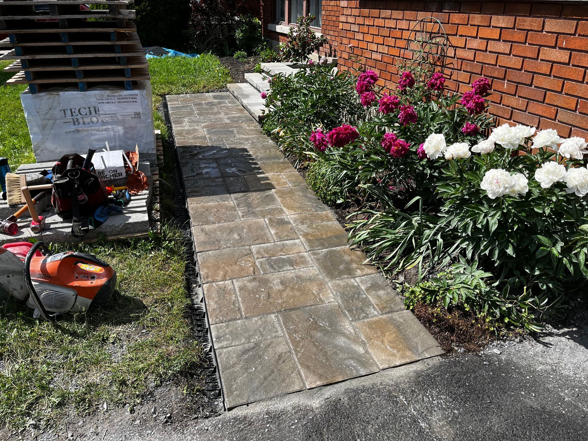 Une passerelle est entourée de fleurs et d'un bâtiment en brique.