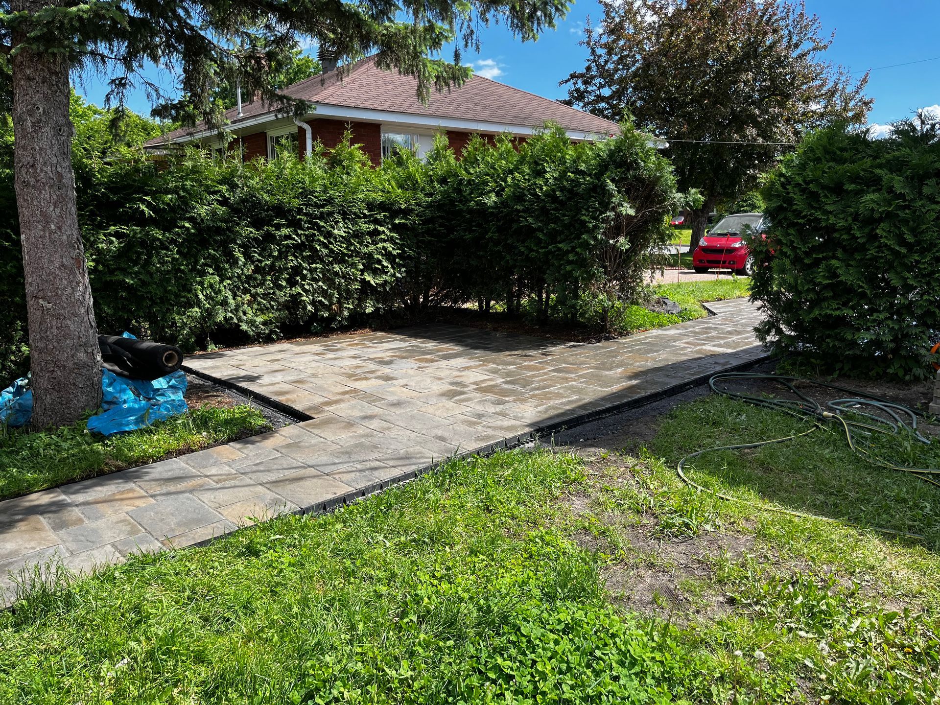 Une voiture rouge est garée dans l'allée d'une maison.