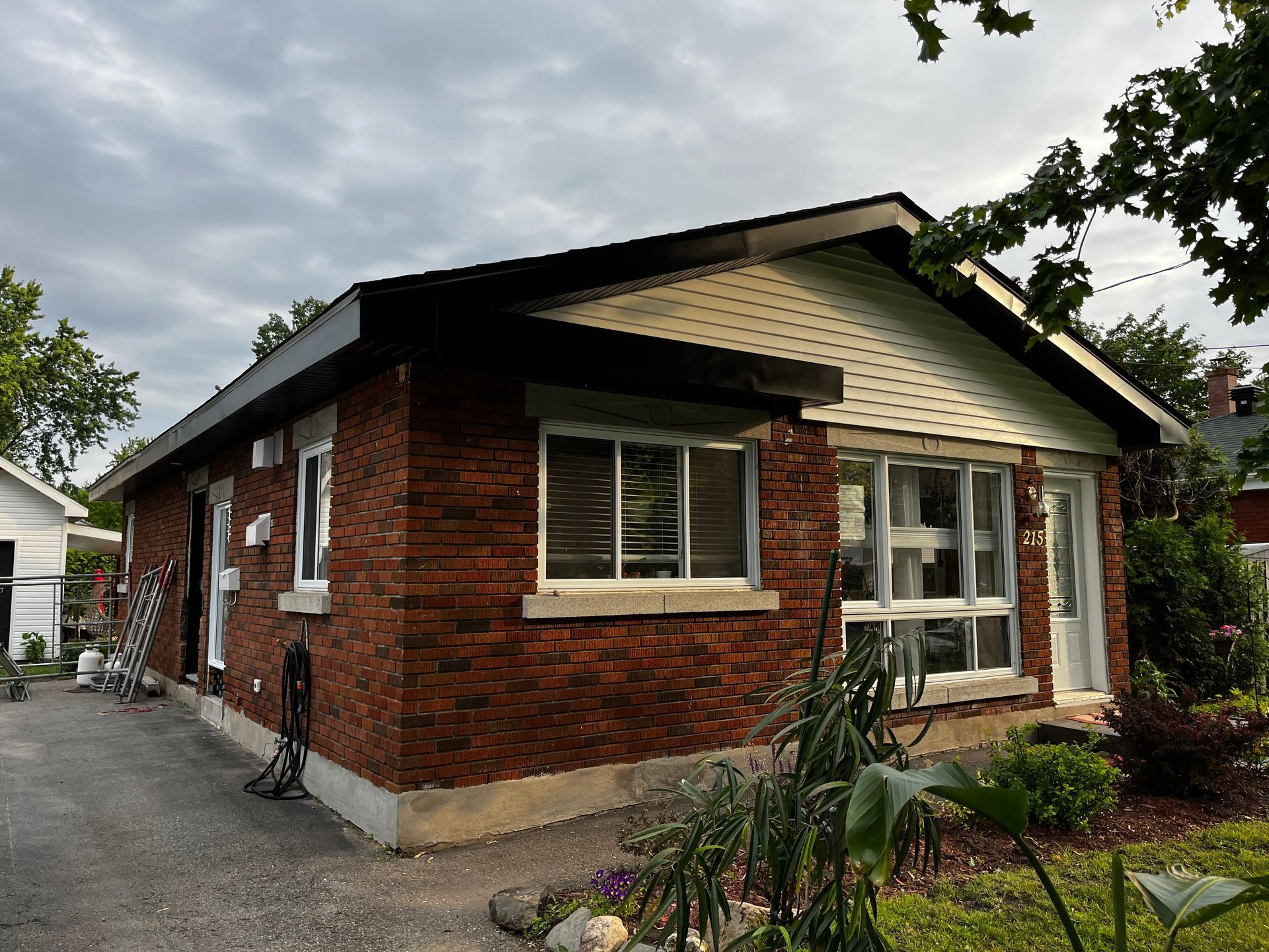 Une maison en brique avec une allée et beaucoup de fenêtres