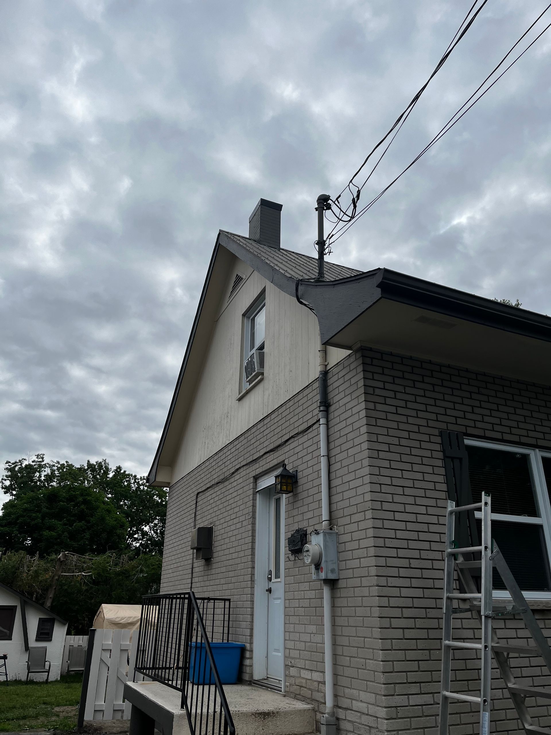 Une maison en brique avec une cheminée sur le toit et une échelle devant.