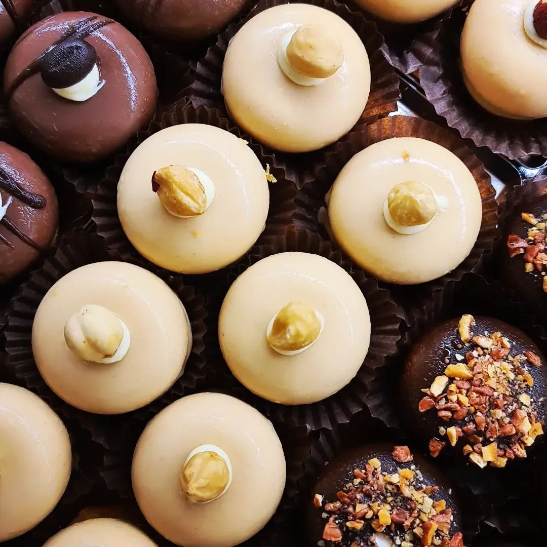 Primo piano di cioccolatini assortiti, alcuni con noci sopra e varie ricoperture, disposti in una scatola.