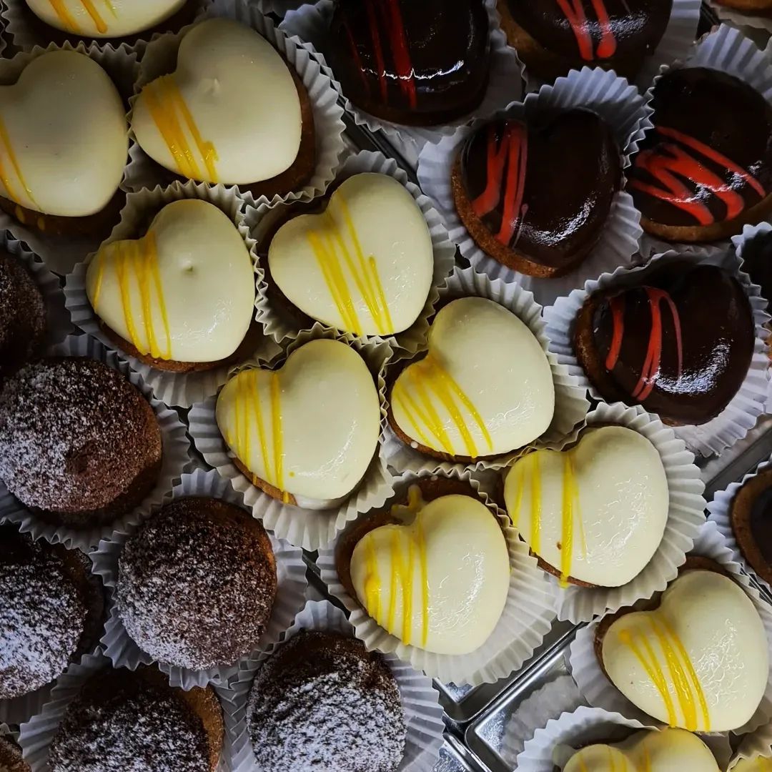 Primo piano di cioccolatini assortiti, tra cui cioccolato bianco a forma di cuore con glassa gialla e cioccolato fondente con strisce rosse.