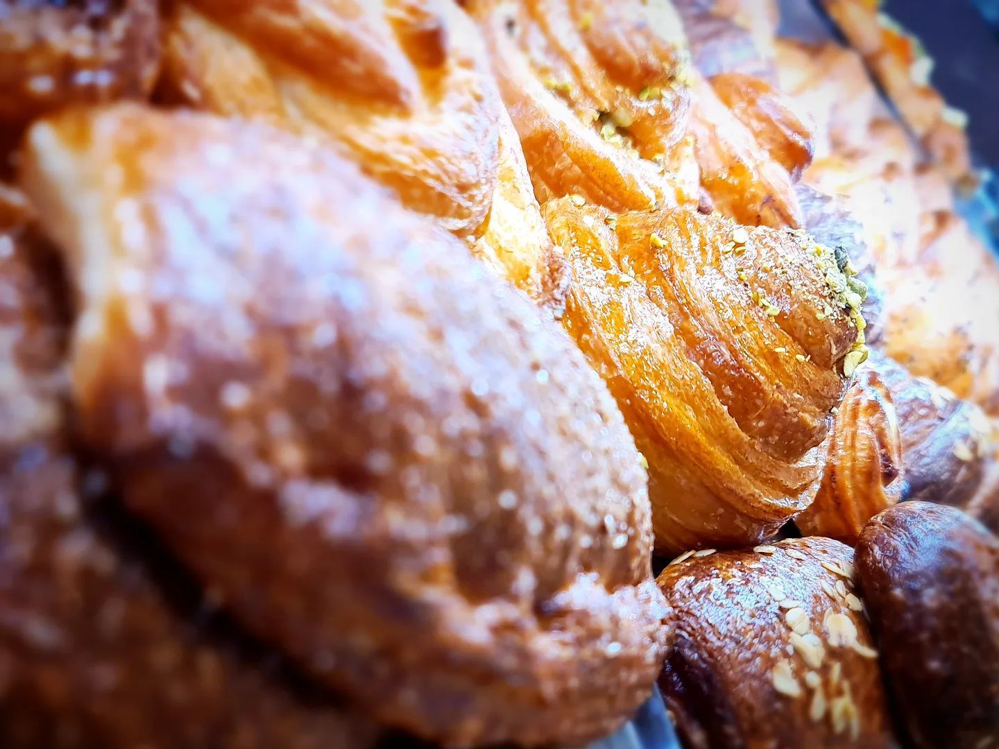 Primo piano di pasticcini assortiti, dorati e friabili, con consistenze e guarnizioni visibili.