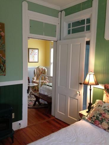 A bedroom with green walls and a bed and a lamp