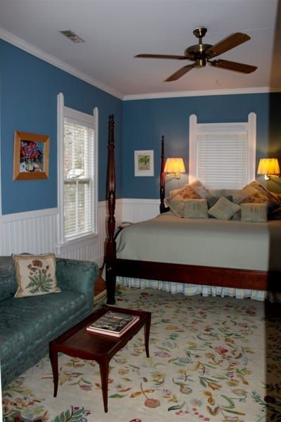 A bedroom with blue walls and a ceiling fan