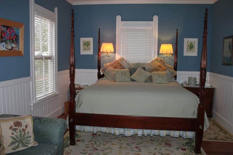 A bedroom with a four poster bed and a chair