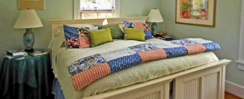 A bed with a colorful quilt and pillows in a bedroom.