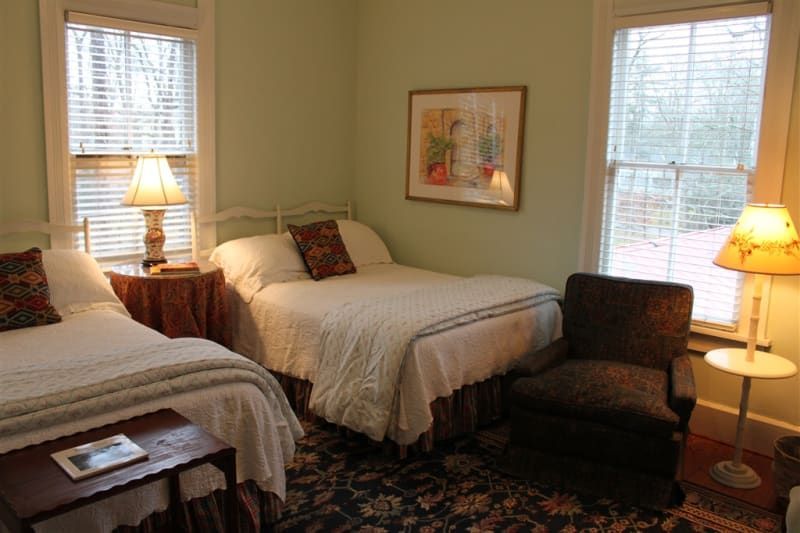 A bedroom with two beds , a chair , lamps and a picture on the wall.