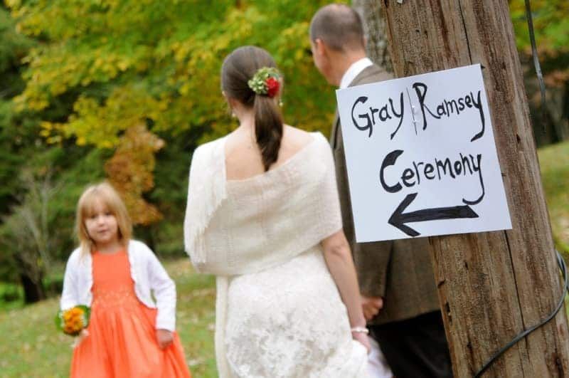 A bride and groom standing next to a sign that says gray ramsey ceremony