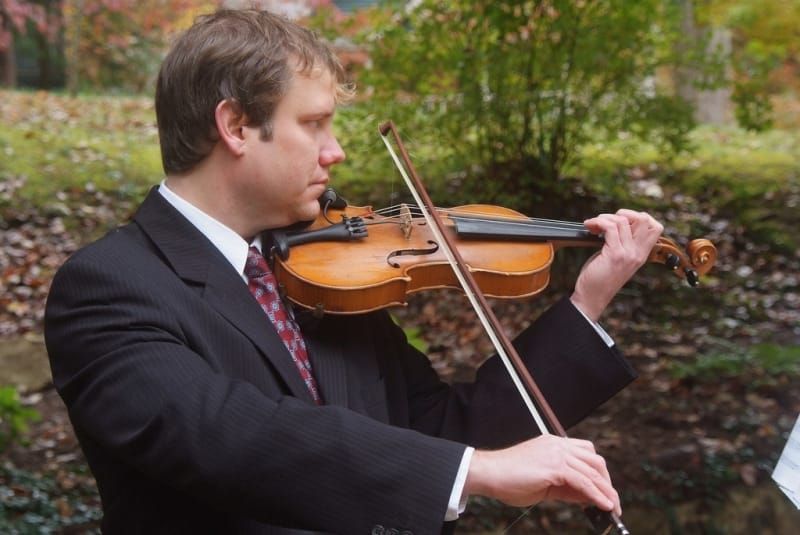 A man in a suit and tie is playing a violin