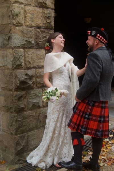 A man in a kilt is standing next to a woman in a wedding dress