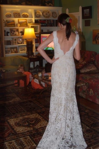 A woman in a white lace dress is standing in a living room
