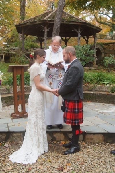 A bride and groom are holding hands during their wedding ceremony