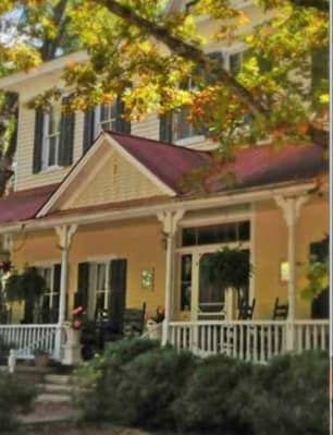 A yellow house with a red roof and a porch