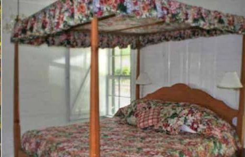 A four poster bed with a floral blanket in a bedroom.