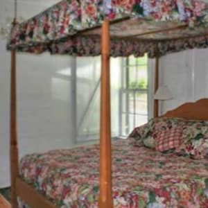 A bedroom with a large bed , two nightstands , a rug , and a chandelier.